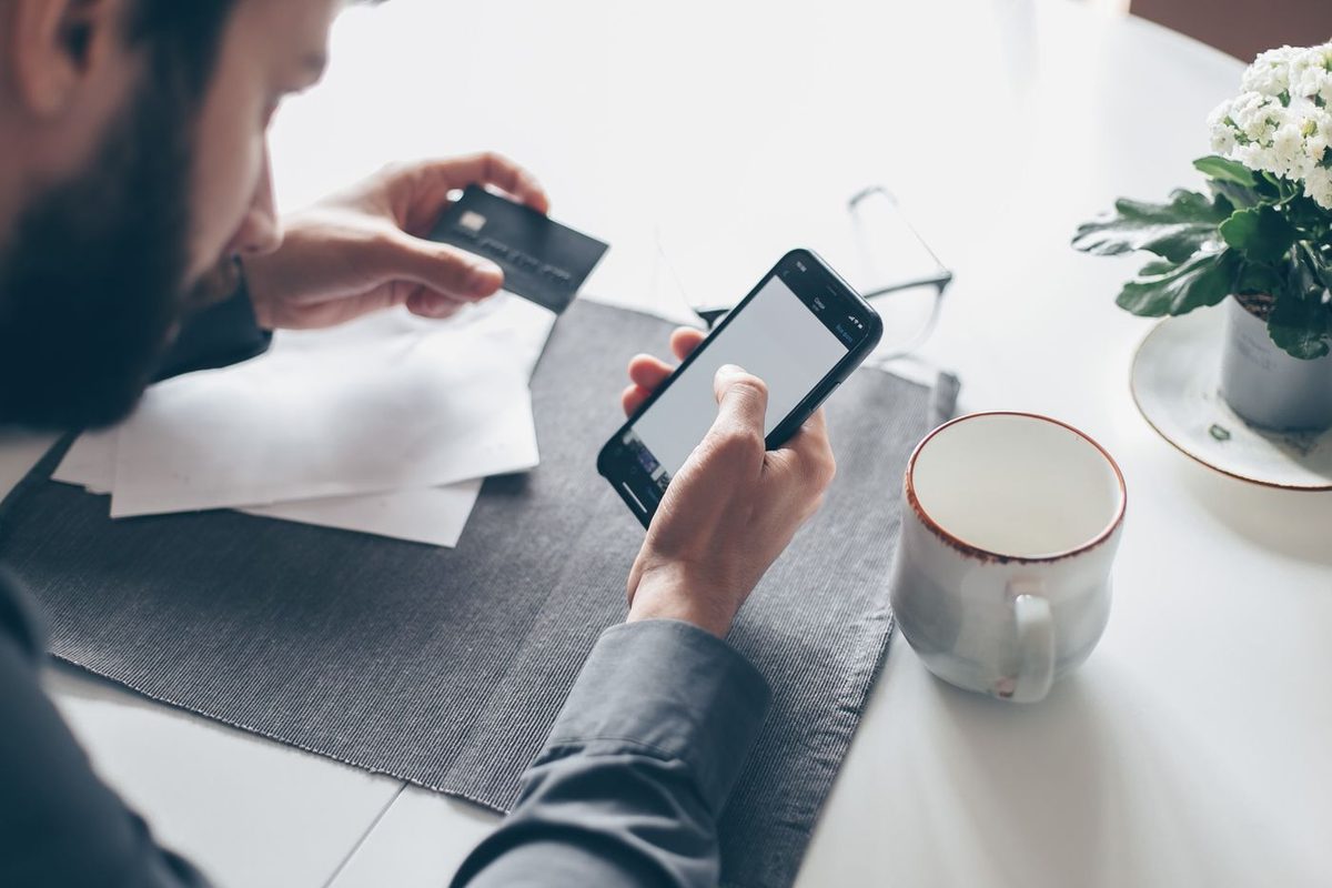Person reviewing their finances on a smartphone at a tidy desk